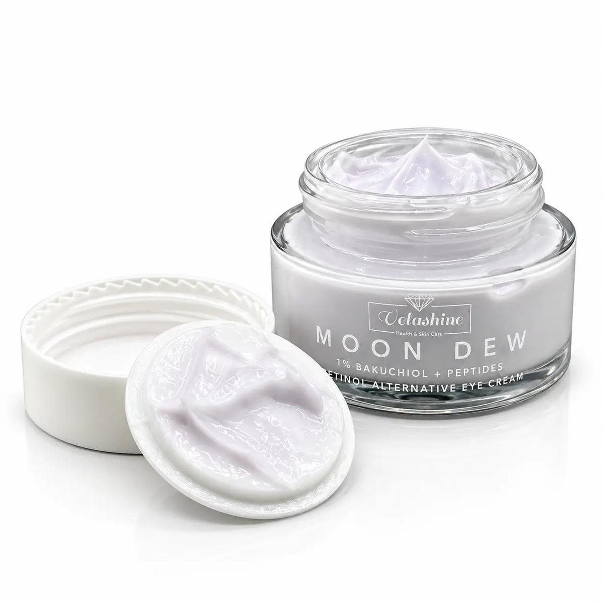 A clear glass jar of Velashine Moon Dew 1% Bakuchol + Peptides Retinol Alternative Eye Cream, shown open with its white lid and a dollop of pale lavender cream in front, on a white background.