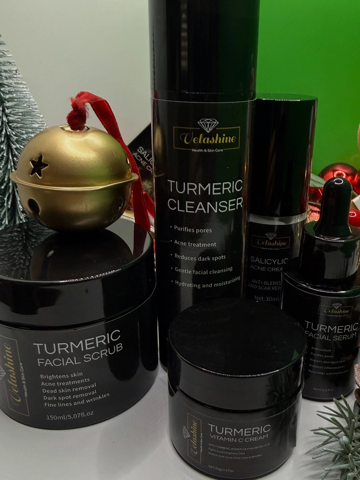 Cosmetic products including a Turmeric Cleanser, Scrub, and Serum with 'Velashine Skincare' branding on a white surface.